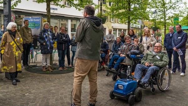 Ein Mann erzählt Rollstuhlfahrern und Menschen ohne Rollstuhl etwas Lustiges